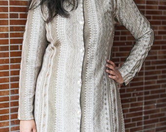 May include: A long, beige button-down dress with detailed patterns. The dress has long sleeves and a mandarin collar. It is fastened with small buttons and is suitable for various occasions. The dress is approximately 140 cm in length.
