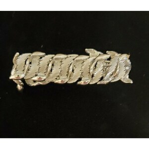 May include: A silver bracelet with a unique, woven design. The bracelet is made of interlocking links that create a wave-like pattern.