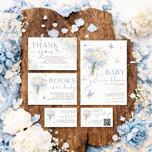Może przedstawiać: Zestaw papeterii na baby shower z kwiatowymi wzorami w odcieniach niebieskiego i białego. Zestaw zawiera zaproszenia, kartki z podziękowaniami i kartę loterii pieluch, wszystkie ozdobione motylami i bukietami kwiatów.