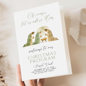 Peut inclure: Une carte de programme de Noël pliée avec le texte "Oh, come, let us adore Him" en écriture élégante. La carte présente une illustration de la scène de la nativité avec trois personnages et un bébé dans une crèche. Le texte "welcome to our CHRISTMAS PROGRAM" est également visible.