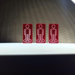 May include: Three red rectangular tiles with a white outline of a person on each tile.