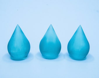 May include: Three blue glass teardrop-shaped ornaments. The ornaments are frosted and have a slightly textured surface.