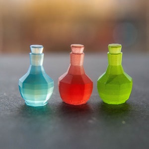 May include: Three small glass bottles with faceted sides. The bottles are filled with colored liquids: blue, red, and green.