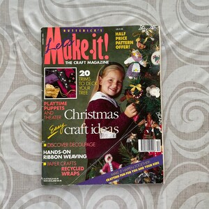 May include: A retro "Make It!" craft magazine with a Christmas theme. The cover shows a girl with a decorated Christmas tree. The magazine's title is in bold, colorful letters, with text promoting craft projects like decoupage and ribbon weaving.