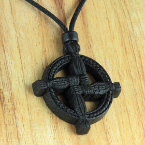 Puede incluir: Collar con colgante de nudo celta de madera negra con cord&oacute;n negro. El colgante es redondo con un dise&ntilde;o de cruz.