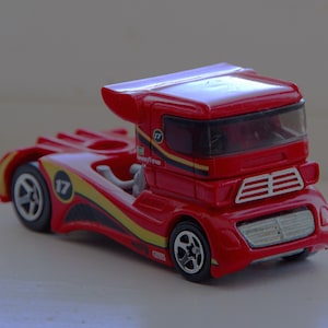 May include: A red toy truck with black and yellow accents. The truck has the number 17 on the side and a Goodyear logo. The cab features a windshield and a spoiler. The wheels are black with silver rims.