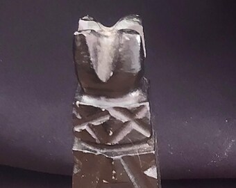 May include: A black carved wooden statue of a person with a geometric design. The statue is about 4 inches tall and has a flat base.