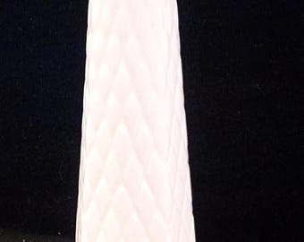May include: A white, textured glass vase with a diamond pattern. The vase has a flared shape and a rounded base. The top of the vase is a solid white color. The vase is displayed against a black background.