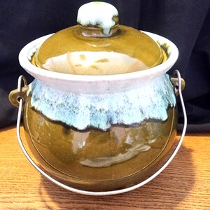 以下が含まれることがあります： 蓋、ハンドル、白い縁が付いた陶器のポット。ポットは緑と青の釉薬で、蓋には白いノブが付いています。ハンドルは金属製です。