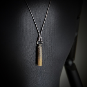 Collar con colgante de cápsula de vial de escondite secreto de latón con pátina en contraste de dos tonos, muy desgastado, con cordón de cuero. Estilo bala, rústico, rockero y bohemio.