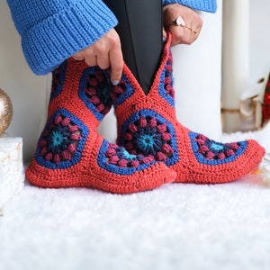 Puede incluir: Botas de ganchillo rojas y azules con un estampado floral. Las botas están hechas de un hilo suave y texturizado y presentan un diseño único y colorido. Las botas son una opción de calzado cómoda y elegante.