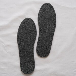 May include: Two gray felt shoe insoles with a stitched edge.