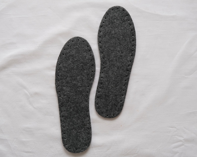 May include: Two gray felt shoe insoles with a stitched edge.