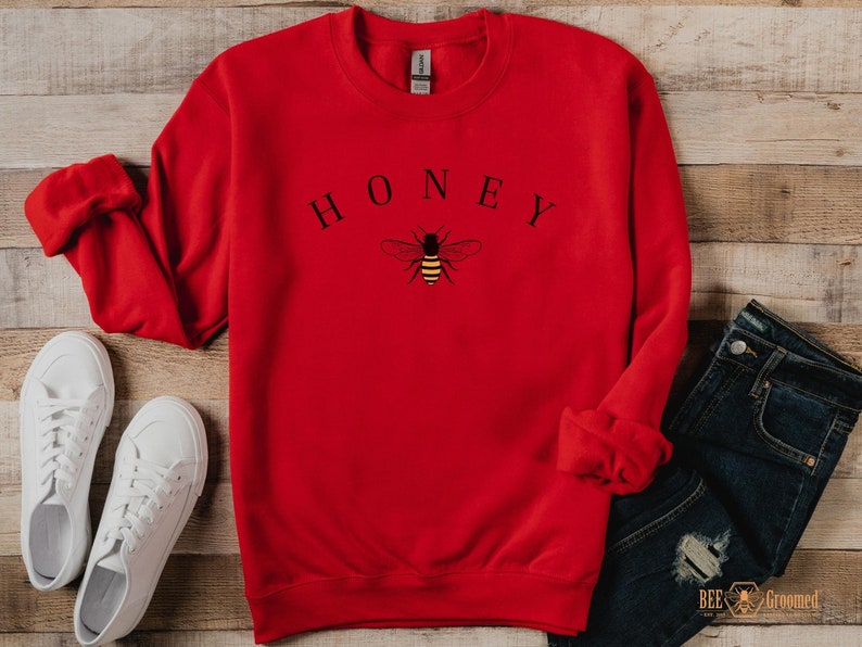 May include: Red sweatshirt with a bee and the word "HONEY" printed on the front.