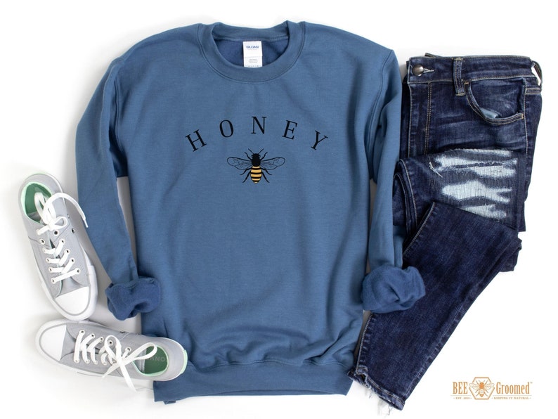 May include: A blue sweatshirt with the word "HONEY" printed in black letters and a small bee graphic in yellow and black.
