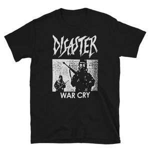 以下が含まれることがあります： 白のグラフィックが特徴の黒いTシャツ。グラフィックには、ギザギザのフォントで「DISASTER」という単語と、ライフルを持った2人の兵士の長方形の画像が含まれています。画像の下には、「WAR CRY」という言葉が白で印刷されています。