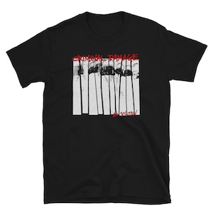 May include: Black t-shirt with a graphic design featuring the text "CRIMINAL DAMAGE" in red above a black and white image and the text "NO SOLUTION" in red below the image. The image appears to be a series of vertical lines.