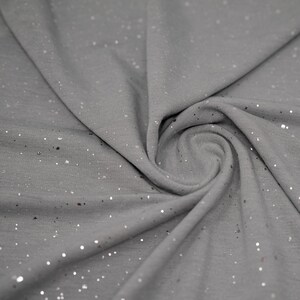 May include: Gray fabric with silver glitter scattered throughout. The fabric is folded and draped.