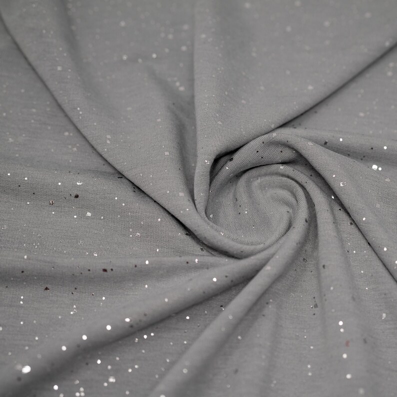 May include: Gray fabric with silver glitter scattered throughout. The fabric is folded and draped.