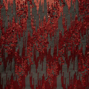 Puede incluir: Tela de lentejuelas roja con un patrón de rayas verticales. Las lentejuelas están dispuestas en un patrón aleatorio, creando un efecto brillante.