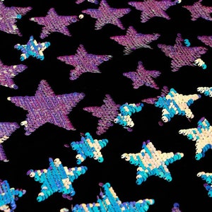 May include: A close-up of iridescent purple and blue star-shaped sequins on a black fabric background.