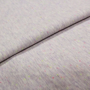 Könnte beinhalten: Nahaufnahme eines hellgrauen Stoffes mit einem gesprenkelten Muster aus rosa und grünen Punkten.