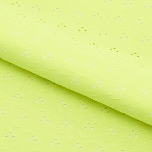 May include: Close-up of a folded piece of bright yellow-green eyelet fabric. The fabric has a textured surface with small, evenly spaced circular cutouts. The eyelet pattern is repeated across the material, creating a delicate, airy look.