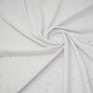May include: White fabric with a subtle sparkle of gold glitter throughout.