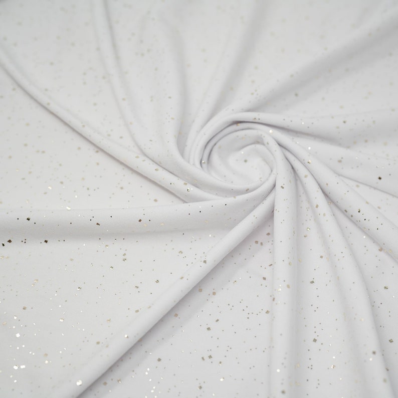 May include: White fabric with a subtle sparkle of gold glitter throughout.