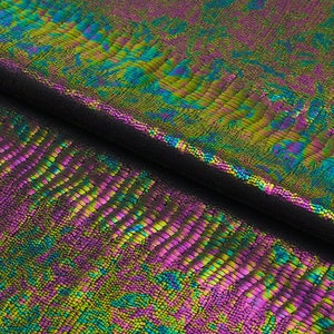 May include: Close-up of iridescent fabric with a snake skin pattern in shades of green, blue, and purple.