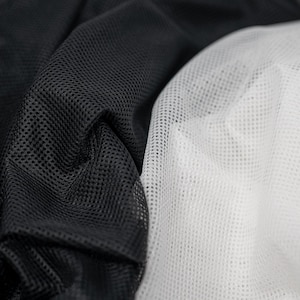 May include: Black and white mesh fabric with a close-up view of the texture. The fabric is soft and breathable.