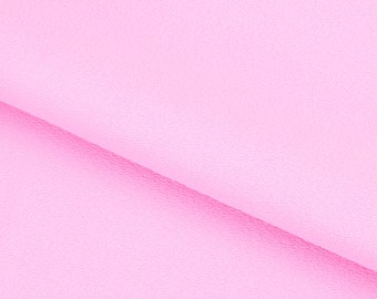 Puede incluir: Primer plano de una tela suave y rosa con una textura sutil. La tela está doblada por la mitad, creando una línea diagonal.