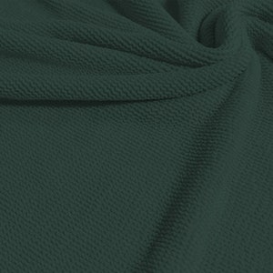 May include: A close-up of a dark green textured fabric. The fabric has a subtle waffle-like pattern.