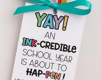 May include: A multi-color pen with a clear plastic casing is attached to a white tag with a teal ribbon. The tag reads "YAY! AN INK-CREDIBLE SCHOOL YEAR IS ABOUT TO HAP-PEN! LOVE,"