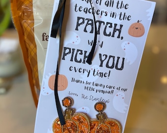May include: A gift tag with the text "Out of all the teachers in the PATCH, we'd PICK YOU every time!" is tied with a black ribbon to a bag. The tag features pumpkin and ghost illustrations. Two beaded pumpkin ornaments are attached.