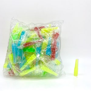 May include: A plastic bag filled with a variety of colorful plastic combs. The combs are in shades of green, blue, and red. The bag is sitting on a white surface.