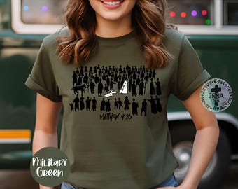 May include: A military green short-sleeve t-shirt featuring a black graphic print of a crowd of silhouettes and one white figure. The text "MATTHEW 9:20" is printed in black below the graphic. A circular logo with a cross is on the right side.