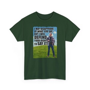Könnte beinhalten: Dunkelgrünes T-Shirt mit einem Aufdruck mit der Aufschrift „I MAY DISAPPROVE OF WHAT YOU SAY, BUT I WILL DEFEND YOUR RIGHT TO SAY IT!“. Die Grafik zeigt einen Mann, der mit einem Gewehr auf einem grasbewachsenen Hügel steht.