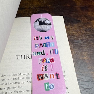 May include: Pink bookmark with a disco ball graphic at the top. The bookmark features the text "it's my party and, I'll read if I WANT to" in a collage style. The bookmark is placed in a book.