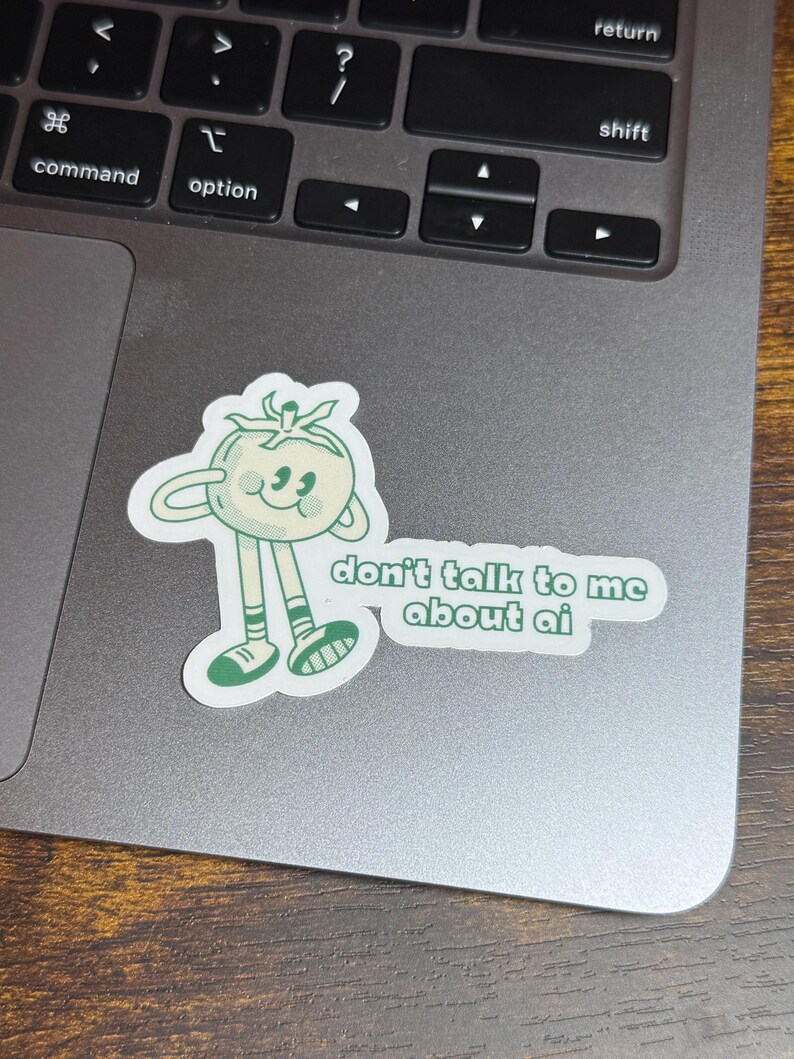 May include: A sticker featuring a cartoon tomato character with arms and legs. The tomato is light green with a smiling face and the text "don't talk to me about ai" in green letters.