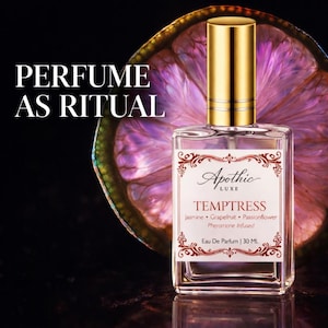 May include: A clear perfume bottle with a gold cap and a label that reads "TEMPTRESS." The bottle is in front of a purple citrus slice. Text above reads "PERFUME AS RITUAL." The bottle contains 30 ML of perfume.