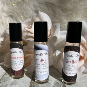 May include: Three glass roller bottles with black caps and labels. The labels are black with white text and feature the name "Apothic Wie" and the names of the scents: "Empire Royalty", "Prodigy", and "Bloodlust". Each bottle contains 10 ml of essential oil blend.