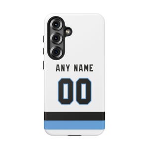 May include: White phone case with a sports jersey design. The case features the text "ANY NAME" above the number "00" in a blue and black design. A black and blue stripe is at the bottom of the case.