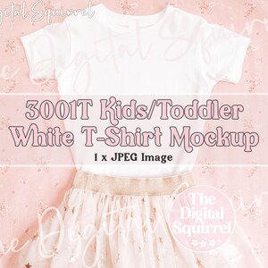以下が含まれることがあります： ピンクの花柄の背景に白い幼児用Tシャツのモックアップ。Tシャツは背景の上に平らに置かれ、その下に金と白のチュールスカートが置かれています。Tシャツの上に「300IT Kids/Toddler White T-Shirt Mockup」というテキストが表示されています。Tシャツの下に「1 x JPEG Image」というテキストが表示されています。