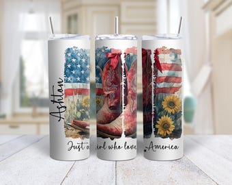 May include: White tumbler with a design featuring the American flag, cowboy boots, and sunflowers. The tumbler has the name "Ashton" and the text "Just a girl who loves America."