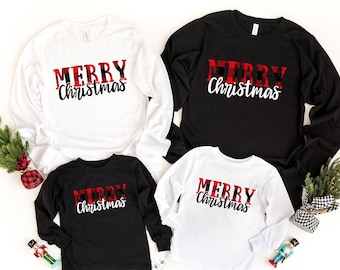 May include: Four long-sleeved shirts with the text "Merry Christmas" in red and black buffalo plaid. Two shirts are white with black text and two shirts are black with white text.