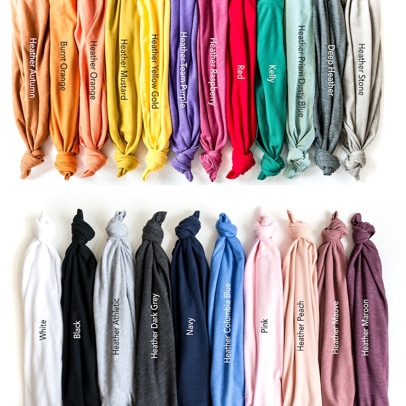 May include: A collection of folded t-shirts in various colors, including white, black, navy, and pink. Each shirt displays a color name, such as "Heather Autumn," "Heather Peach," and "Red." The shirts are arranged against a white background.