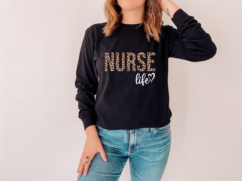 K&ouml;nnte beinhalten: Schwarzes Langarmshirt mit einem Leopardenmuster "NURSE life"-Aufdruck.