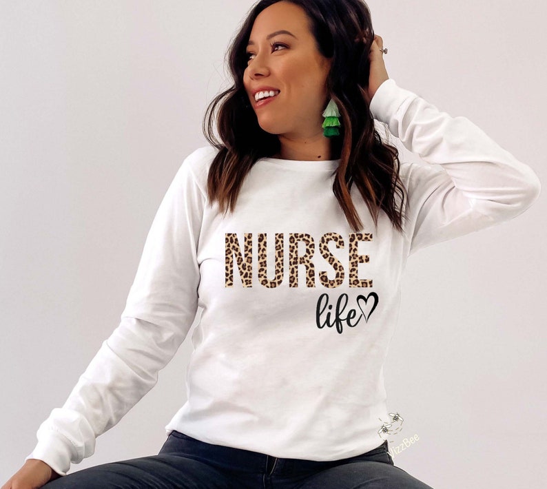 K&ouml;nnte beinhalten: Wei&szlig;es Langarmshirt mit einem Leopardenmuster "NURSE life"-Aufdruck.