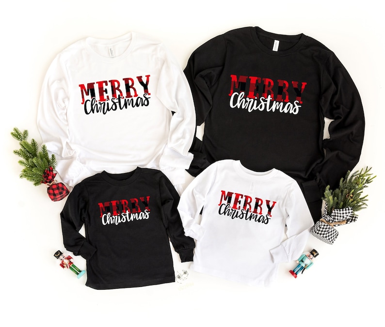 May include: Four long-sleeved shirts, two white and two black, with the text "MERRY Christmas" in a red and black plaid design. The shirts are arranged together, suggesting a family set, with holiday decorations.